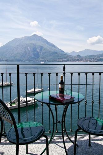 a table and chairs on a balcony with a view of the water at Albergo Milano in Varenna