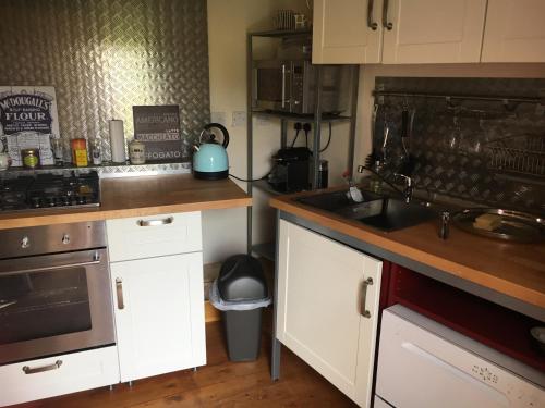 a kitchen with a sink and a stove top oven at Holly Cottage in Banbury