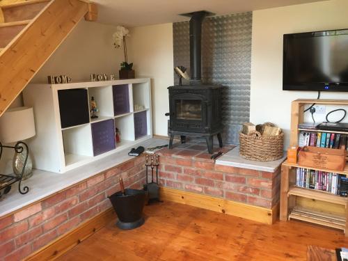 - une cheminée en briques dans le salon avec cuisinière dans l'établissement Holly Cottage, à Banbury