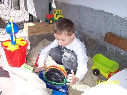 a young boy playing in the sand with his toys at Ferienhaus Sternhof in Mieders