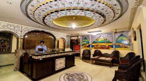 a man standing at a counter in a room with a ceiling at Nahargarh Haveli-Near Train station Metro in Jaipur