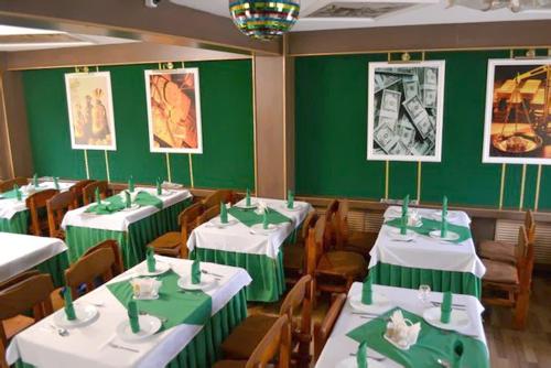ベロレツクにあるHotel "Bankir"の緑の壁と白いテーブルと椅子が備わるレストラン