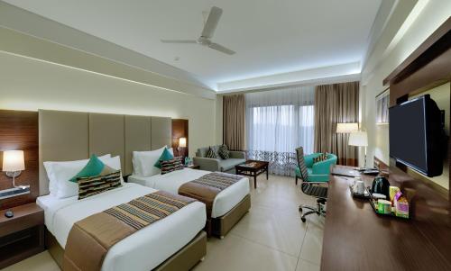 a hotel room with two beds and a flat screen tv at The Fern Kadamba Hotel And Spa in Old Goa