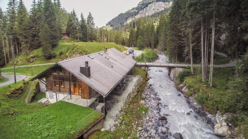 a house on a hill next to a river at Griesalp Hotels in Kiental