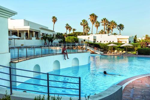 - une piscine avec une personne dans l'eau dans l'établissement CALIMERA Delfino Beach Resort & Spa, à Nabeul