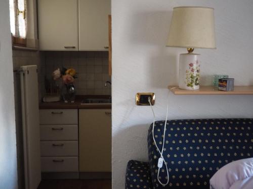 Zimmer mit einem Bett und einer Küche mit einer Lampe in der Unterkunft monolocale in villa in Macugnaga