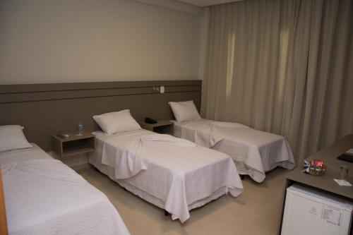 a hotel room with three beds and a television at Pak Suítes Hotel in Luis Eduardo Magalhaes