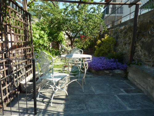 a patio with a table and chairs and flowers at Le Village in Montjovet