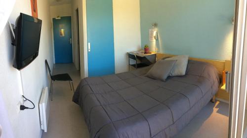a bedroom with a bed and a flat screen tv at Hotel Bains Sarrailh in Dax