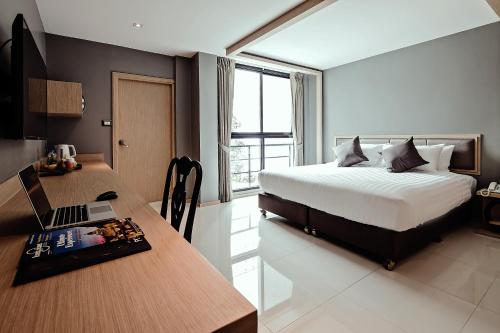 a bedroom with a bed and a desk with a laptop at Three Sukhumvit Hotel - SHA Plus Certified in Bangkok