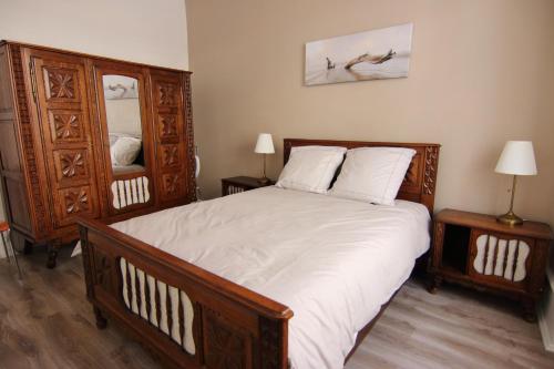 - une chambre avec un grand lit en bois et des draps blancs dans l'établissement Le Jules, à Colmar