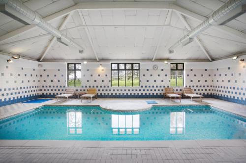 a large swimming pool with chairs and a table at Leonardo Hotel East Midlands Airport in Castle Donington