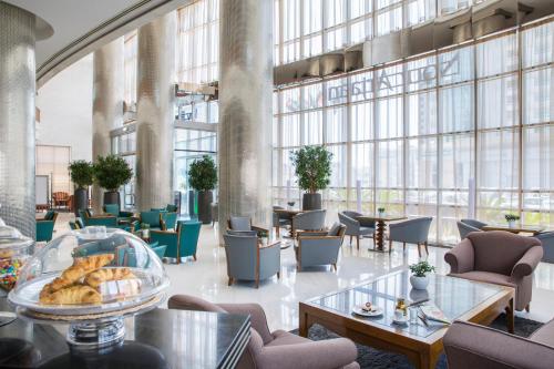 - un hall avec des tables, des chaises et de grandes fenêtres dans l'établissement Nour Arjaan by Rotana-Fujairah, à Fujaïrah