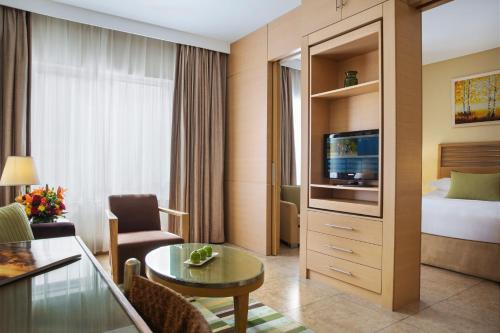 a hotel room with a bed and a television at Nour Arjaan by Rotana-Fujairah in Fujairah