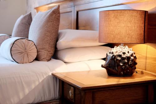 a lamp on a table next to a bed with pillows at The Coach House Inn in Chester