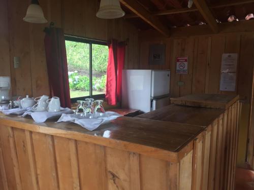 a kitchen with a wooden counter with sinks and a refrigerator at Hotel Chalets Los Volcanes in Alajuela City