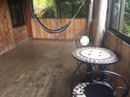 a porch with a hammock and a table and chairs at Hotel Chalets Los Volcanes in Alajuela City