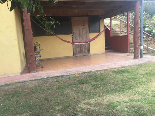 a house with a porch with a door and a yard at Hotel Chalets Los Volcanes in Alajuela City