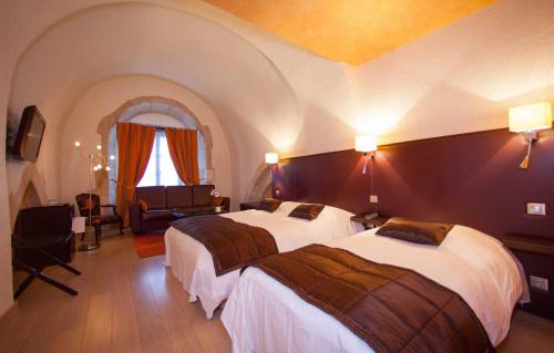 a hotel room with two beds and a chair at Logis H&ocirc;tel Le Cheval Blanc in Langres