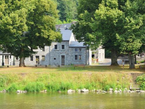 una casa de piedra junto a un río con árboles en between town of Spa and Durbuy a lovely cottage, en Hamoir
