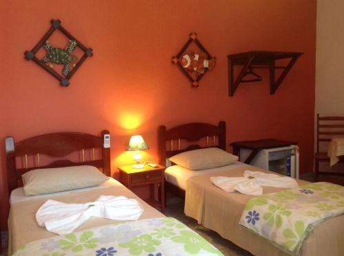 2 Betten in einem Zimmer mit orangefarbenen Wänden in der Unterkunft Pousada Telhado Azul in Abraão