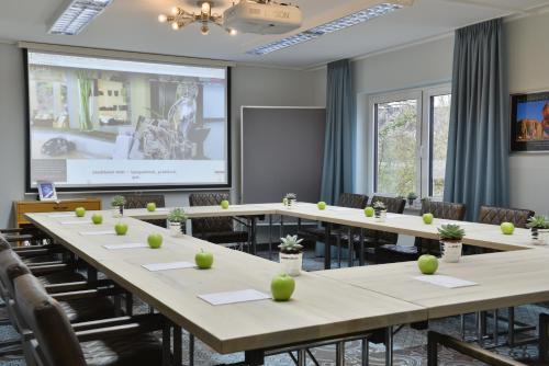 a conference room with tables and chairs and a projection screen at Hotel Uhu Garni - Superior in Cologne