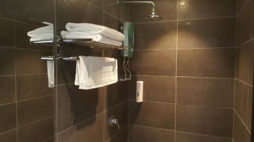 a bathroom with a shower with white towels in it at 9 Square Hotel - Seri Kembangan in Seri Kembangan