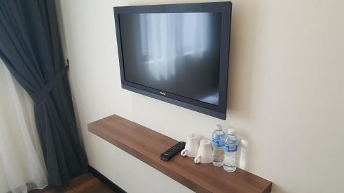 a television on a wall with bottles of water on a shelf at 9 Square Hotel - Seri Kembangan in Seri Kembangan