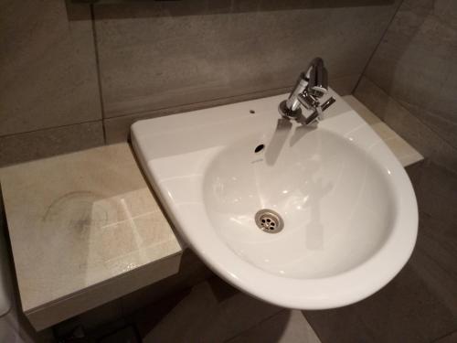 a white sink in a bathroom with a facet at 9 Square Hotel - Seri Kembangan in Seri Kembangan