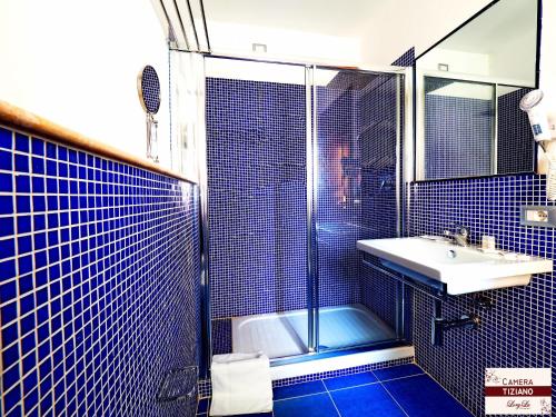 y baño de azulejos azules con lavabo y ducha. en LoryLu, en Tropea