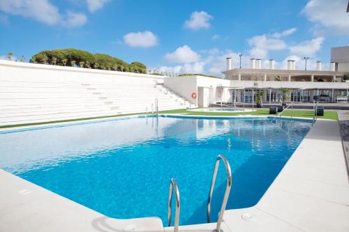 a swimming pool with chairs in front of a building at Hotel Puerto Sherry in El Puerto de Santa María