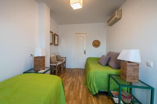 セビリアにあるGalera Donkey Terraza Privadaのベッドルーム1室(緑のベッド1台、ランプ付きテーブル2台付)