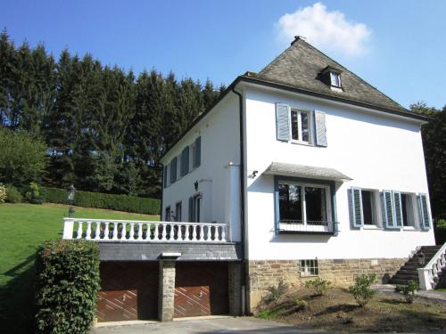 a white house with a porch and a yard at Luxurious countryside holiday home with pool in Malmedy