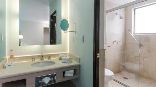 uma casa de banho com um lavatório, um WC e um espelho. em Holiday Inn & Suites Mexico Zona Reforma, an IHG Hotel em Cidade do México