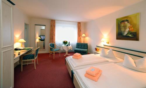 バート・ファリングボステルにあるホテル シュネハーゲンのベッド2台とデスクが備わるホテルルームです。