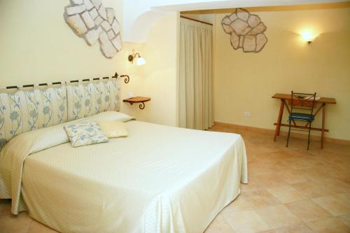 Un dormitorio con una cama blanca y una mesa. en Hotel Tirrena Bike & Country Hotel, en Portoferraio