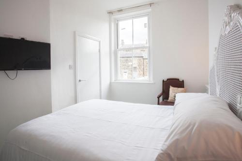 a white bedroom with a large bed and a window at The Lodge Harrogate in Harrogate
