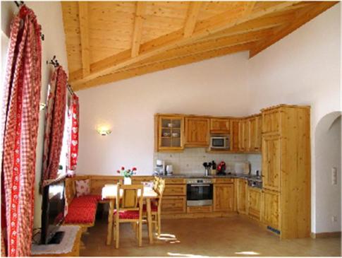 eine Küche mit Holzschränken und einem Tisch im Zimmer in der Unterkunft Apartment Großvenedigerblick in Neukirchen am Großvenediger
