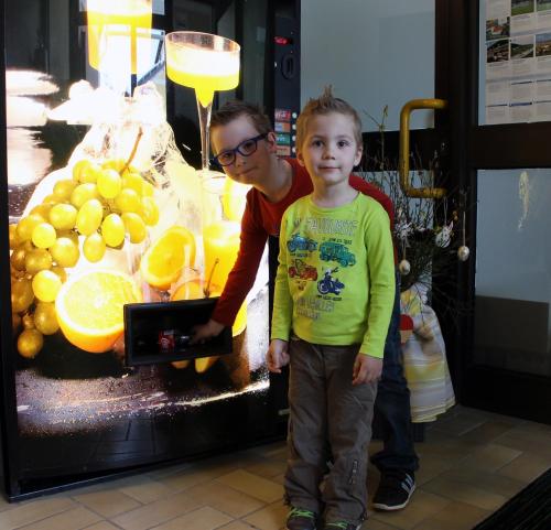 a man and a young boy standing in front of a fruit machine at Post Hostel For Youth, Students and Pilgrims in Lavamünd