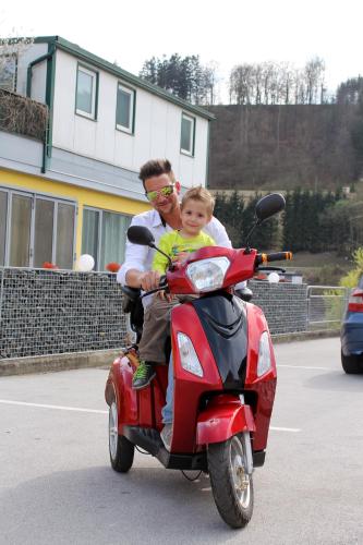 a man and a child riding a red scooter at Post Hostel For Youth, Students and Pilgrims in Lavamünd