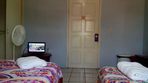 a room with two beds and a white door at Don Santiago Guesthouse Downtown in San Ignacio