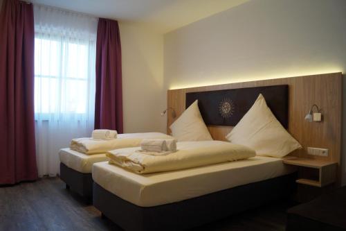 two beds in a hotel room with red curtains at Hotel Gasthaus Sonne in Peißenberg