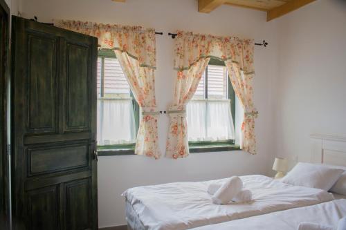a bedroom with a bed and two windows at BÉNI family wine farm in Cegléd