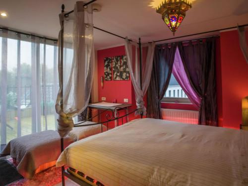 a bedroom with red walls and a bed with a chandelier at Very nice manor house in North African atmosphere in Kortrijk