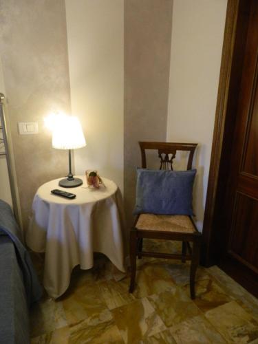 a table with a lamp and a chair in a room at Affittacamere Casa Mac & Rose in San Quirico dʼOrcia