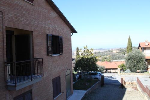 un edificio in mattoni con balcone sul lato di Affittacamere Casa Mac & Rose a San Quirico dʼOrcia