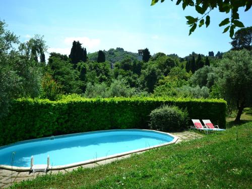 a swimming pool with two chairs and a hedge at Charming holiday home 4km from Lucca with a private pool in Lucca