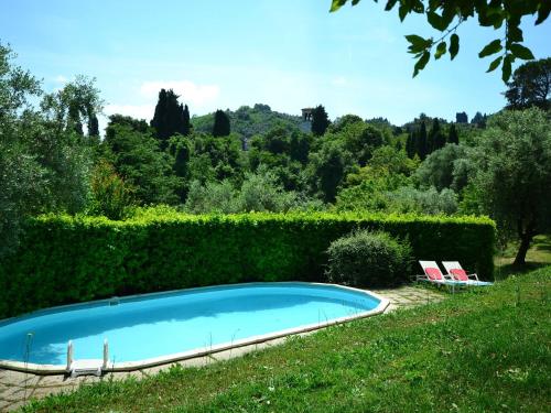 uma piscina com duas cadeiras e uma sebe em Charming holiday home 4km from Lucca with a private pool em Lucca