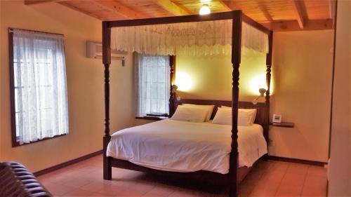 1 dormitorio con cama con dosel y sábanas blancas en Heatherlie Cottages Halls Gap, en Halls Gap