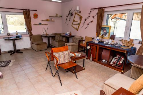 Noring Guest House في Lupeni: غرفة معيشة مع كراسي وطاولات ونوافذ